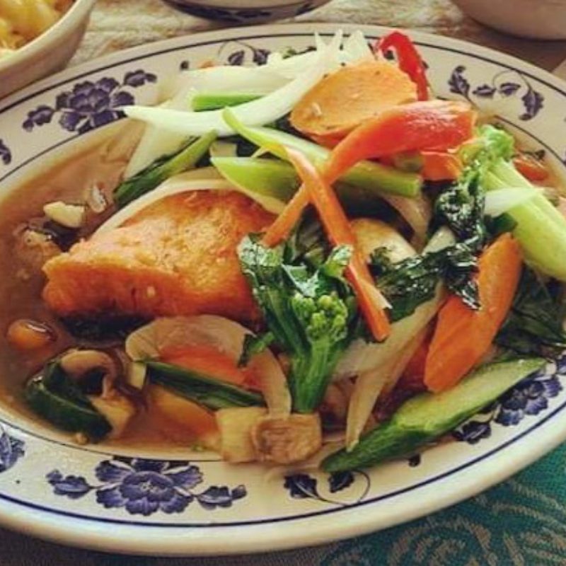 A plate of stir-fried vegetables with tofu on a patterned plate, with a side of macaroni.