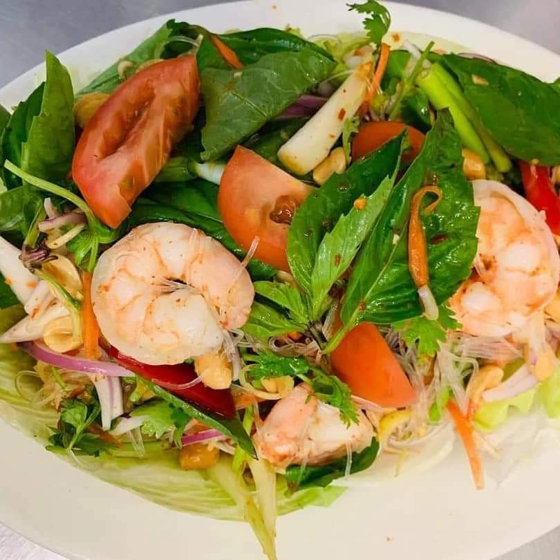 A fresh shrimp salad with mixed greens, tomatoes, onions, and herbs.